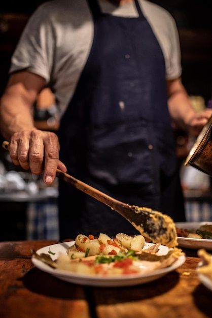 Foto middelsectie van chef-kok die eten op een bord serveert in een restaurant