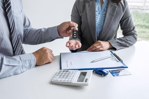 Middelsectie van een agent die een autosleutel geeft aan een vrouw op kantoor