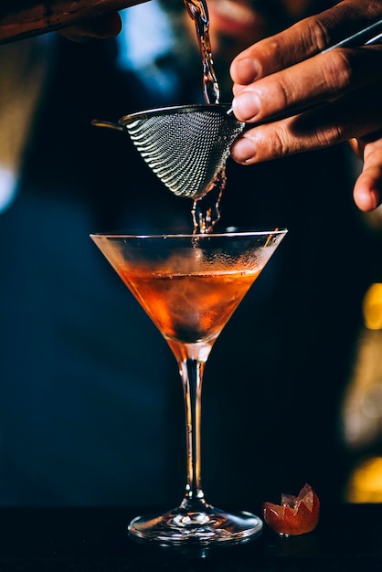 Middelsectie van een barman die een cocktail bereidt in een bar