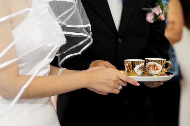 Foto middelsectie van een bruidspaar met theekopjes in een bord