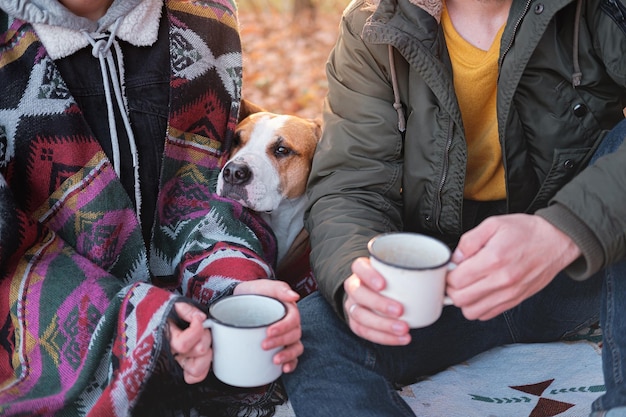 Foto middelsectie van een koppel met een koffiekopje dat buiten met een hond zit