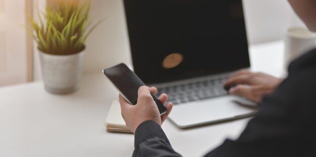 Middelsectie van een man die een laptop op tafel gebruikt