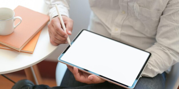 Middelsectie van een man die een smartphone op tafel gebruikt