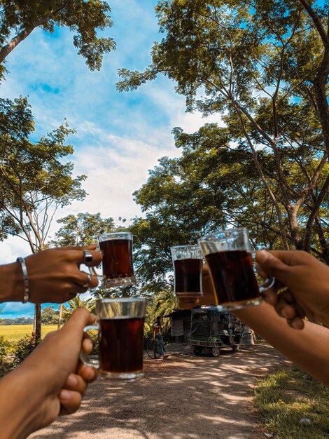 Foto middelsectie van een man die een theeglas tegen de lucht houdt