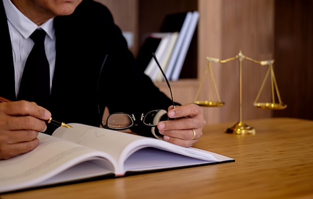 Middelsectie van een mannelijke advocaat die aan zijn bureau op een boek schrijft