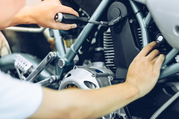 Foto middelsectie van een mechanicus die een motorfiets in een garage repareert