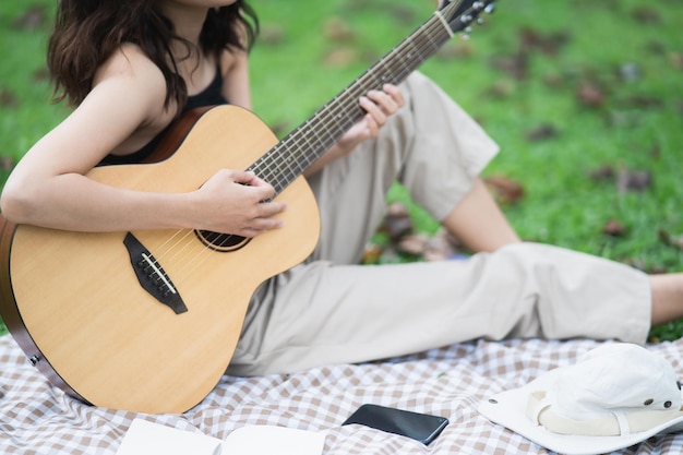 Middelsectie van een meisje dat gitaar speelt terwijl ze buiten zit