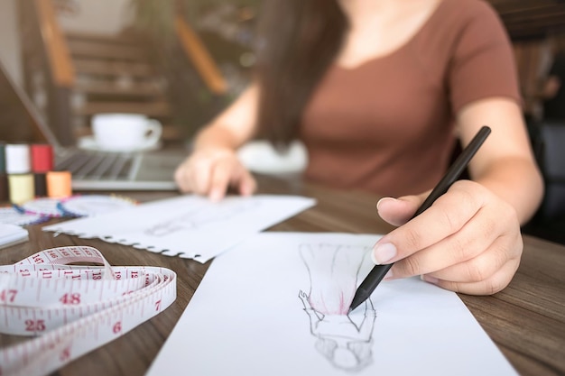 Middelsectie van een modeontwerper die schetsen op een spiraalvormig notitieboek aan het bureau