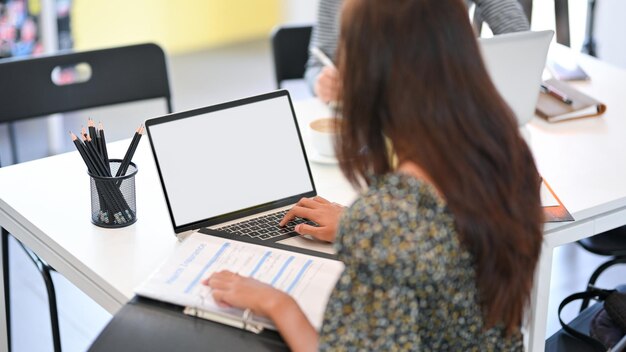 Middelsectie van een vrouw die een mobiele telefoon gebruikt terwijl ze op tafel zit