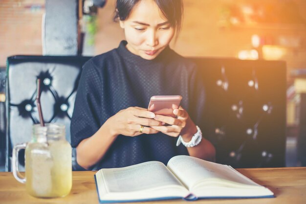 Middelsectie van een vrouw die een mobiele telefoon op tafel gebruikt
