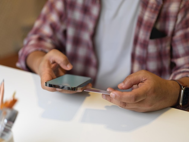 Foto middelsectie van een vrouw die een smartphone op tafel gebruikt