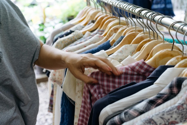 Middelsectie van een vrouw die kleding uit een rek in de winkel kiest voor verkoop