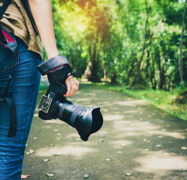 Middelsectie van een vrouw met een camera tegen bomen