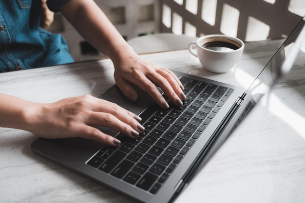 Middelsectie van een vrouw met een laptop aan tafel