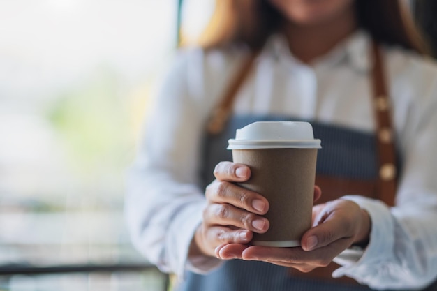 Middelsectie van serveerster die koffie geeft in een wegwerpbeker in een café