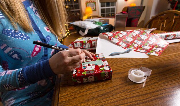 Foto middelsectie van vrouw die kerstcadeaus op tafel verpakt thuis