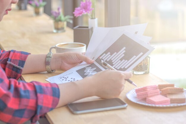 Foto middelsectie van zakenvrouw die documenten onderzoekt in een café