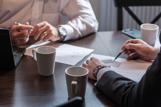 Middelsection van zakenmensen die met koffiekopjes op het bureau werken