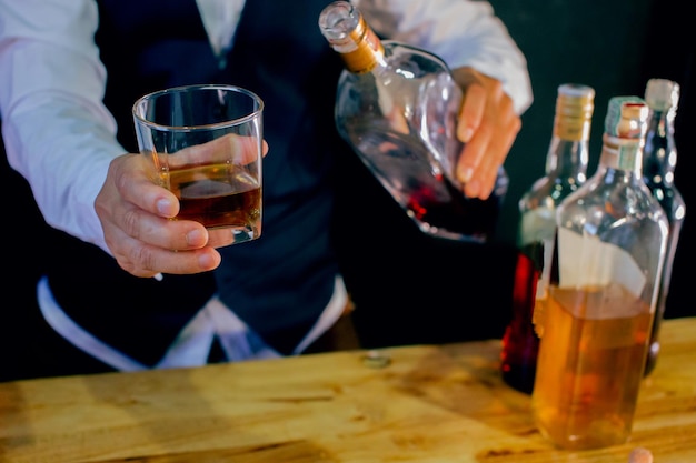 Middelsnede van barman die whisky in glas vasthoudt bij de bar