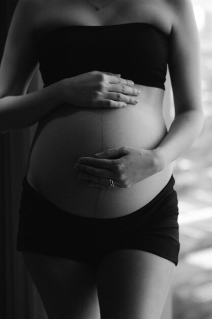 Middelsnede van de hand van een zwangere vrouw op de buik