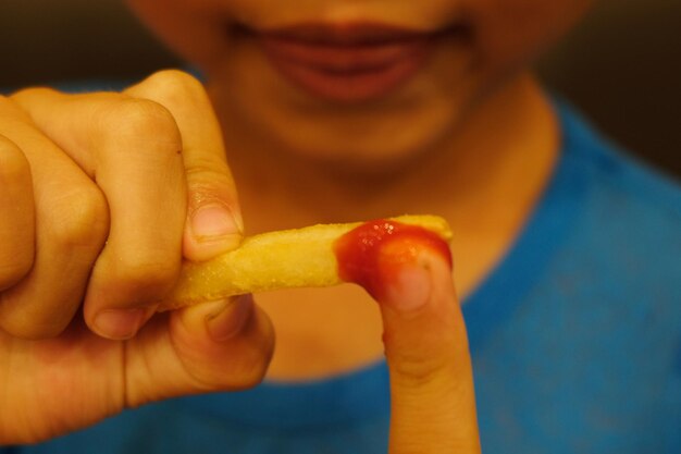 Middelsnede van een jongen die friet eet.
