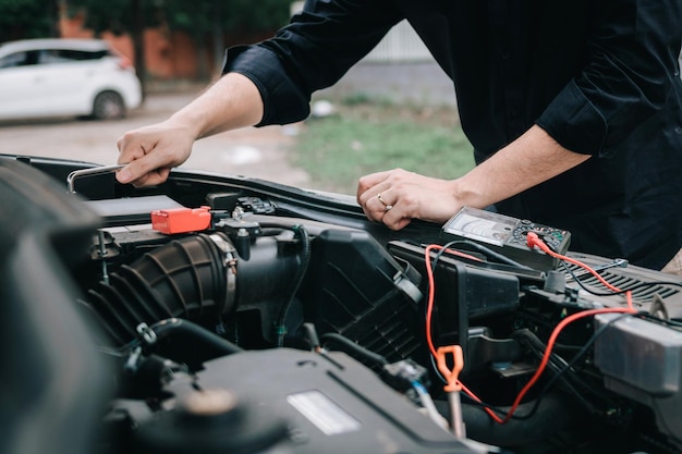 Middelsnede van een man die de motor van een auto aan het repareren is aan de kant van de weg
