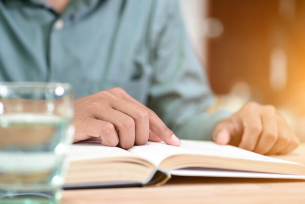 Middelsnede van een man die een boek op tafel leest