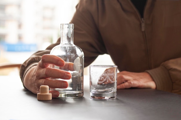 Foto middelsnede van een man die een glazen fles op tafel houdt