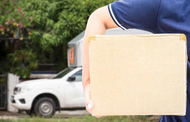 Foto middelsnede van een man die een kartonnen doos tegen een auto houdt