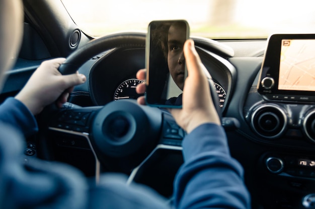 Middelsnede van een man die een mobiele telefoon in de auto gebruikt