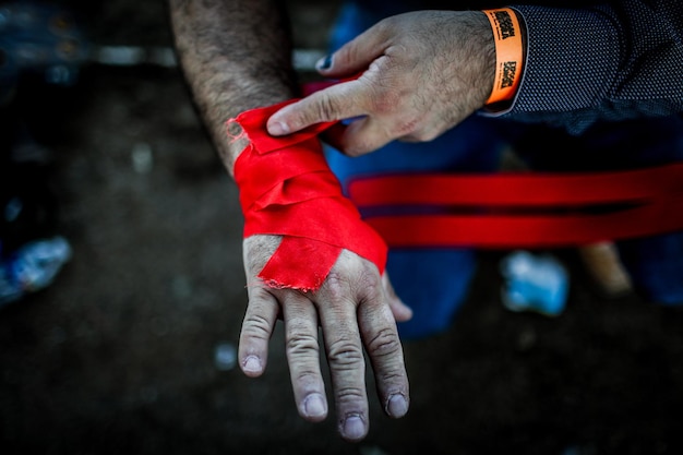 Middelsnede van een man die een rood verband op de hand verpakt