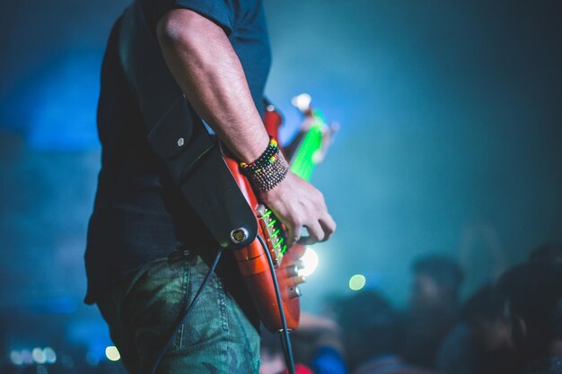 Foto middelsnede van een man die gitaar speelt terwijl hij op het podium staat