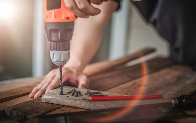 Middelsnede van een man die in een werkplaats in een plank boort
