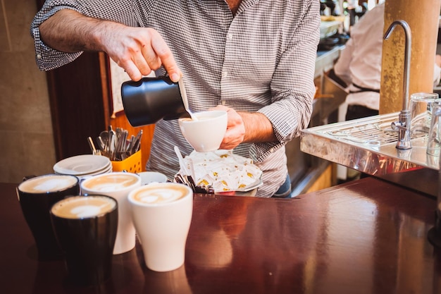 Middelsnede van een man die schuimkunst maakt in een koffiekop
