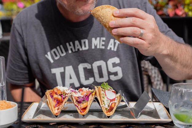 Foto middelsnede van een man die tacos eet.