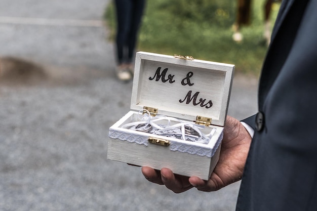Middelsnede van een man die tijdens een huwelijksceremonie ringen in een doos houdt