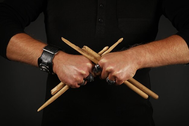 Foto middelsnede van een man met gebroken drumsticks terwijl hij tegen een zwarte achtergrond staat