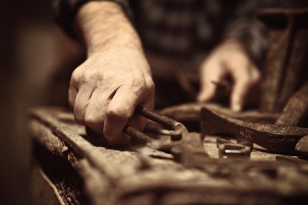 Foto middelsnede van een mannelijke schoenmaker met gereedschap in een werkplaats