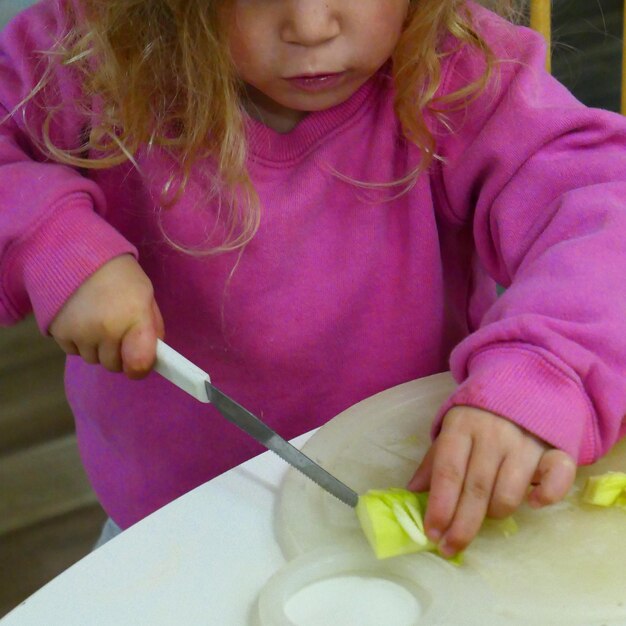 Foto middelsnede van een meisje dat eten op tafel snijdt
