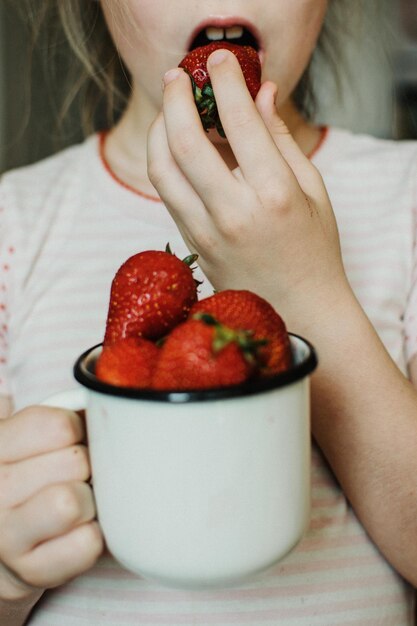 Foto middelsnede van een meisje dat thuis fruit eet.