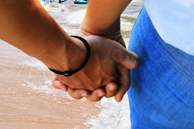 Foto middelsnede van een paar dat elkaar de hand houdt op het strand