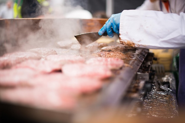 Middelsnede van een persoon die een burger bereidt op een straatmarkt