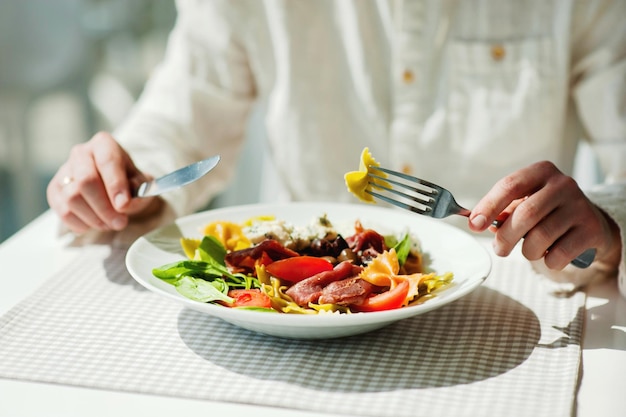 Middelsnede van een persoon die pasta vasthoudt in een restaurant