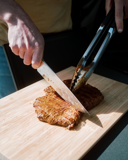 Foto middelsnede van een persoon die vlees op een snijplank bereidt