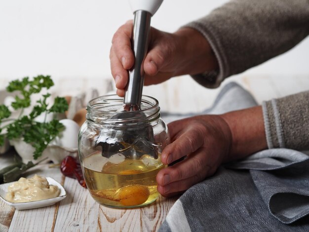 Foto middelsnede van een persoon die voedsel bereidt in een glazen pot op tafel