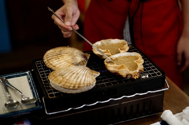 Foto middelsnede van een persoon die zeevruchten op een barbecue grill bereidt