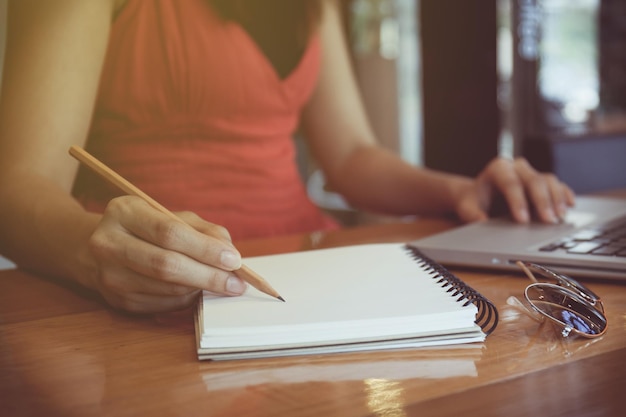 Middelsnede van een vrouw die aan tafel zit en op een boek schrijft