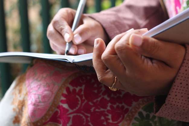 Middelsnede van een vrouw die buiten op een boek schrijft