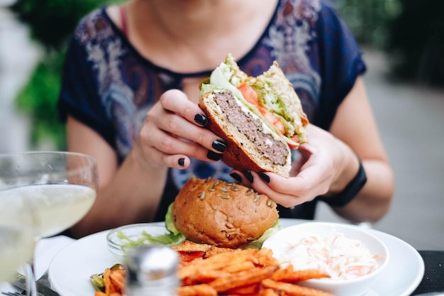 Middelsnede van een vrouw die een burger in een restaurant vasthoudt