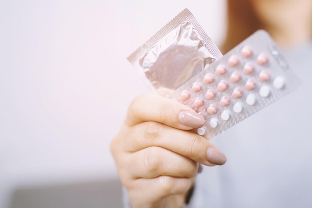 Middelsnede van een vrouw die een condoom en een blisterpakket vasthoudt